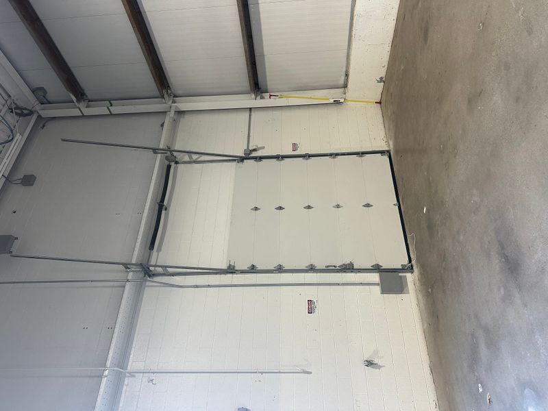 Large commercial insulated sectional door interior with track hardware and spring system — MA