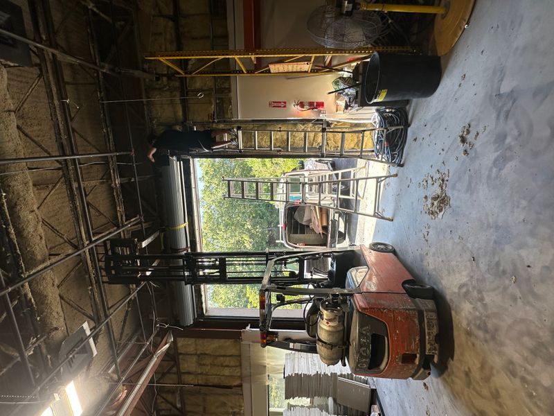 Commercial warehouse with overhead door and forklift during door service in MA