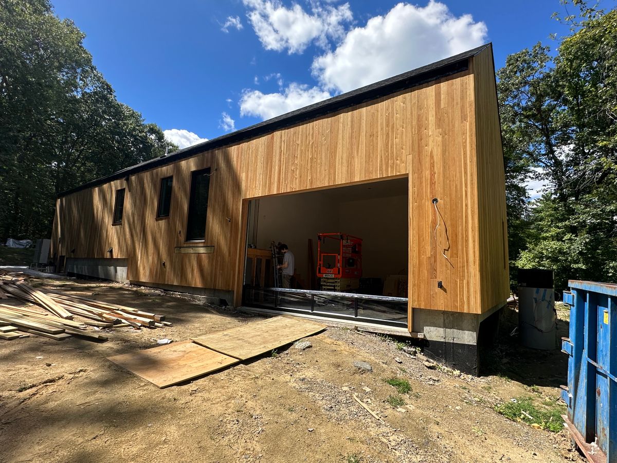 Modern cedar building with large garage opening under construction in Massachusetts