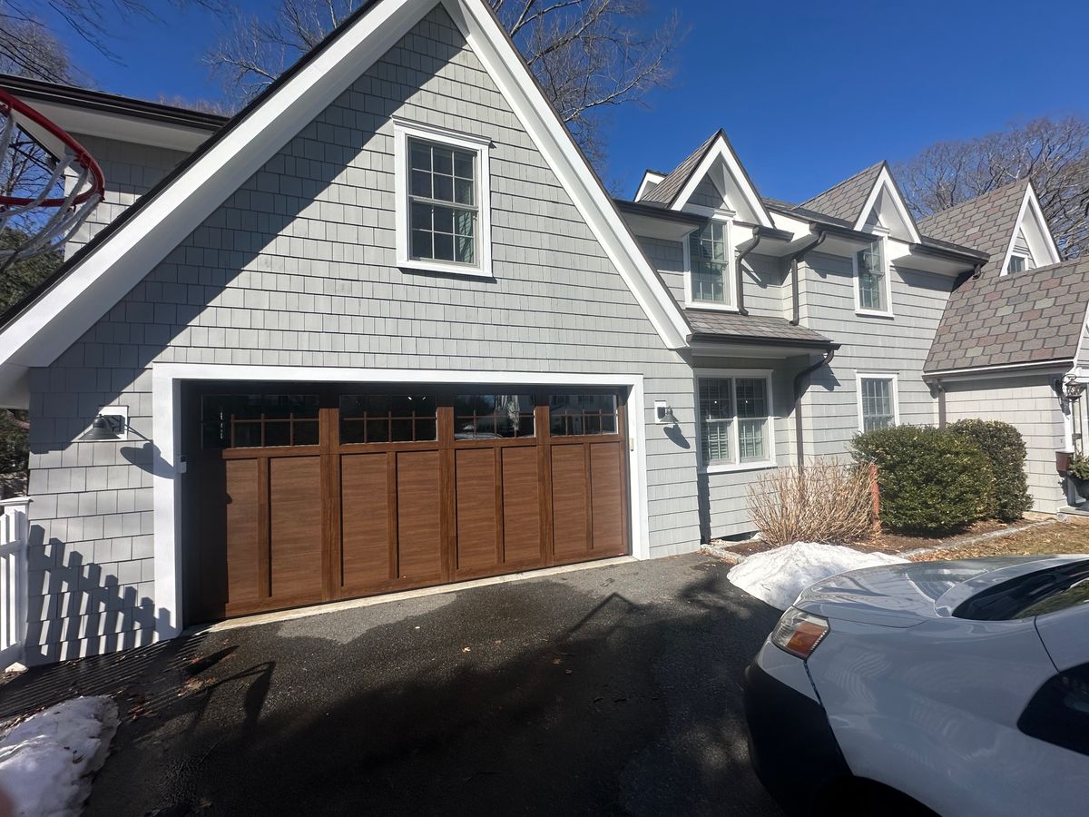 Wood garage door installation with snow on ground — winter service in Massachusetts